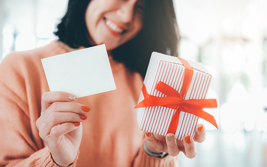Idée cadeau d'entreprise : une salariée tenant un cadeau emballé et une carte vierge pour un message personnel
